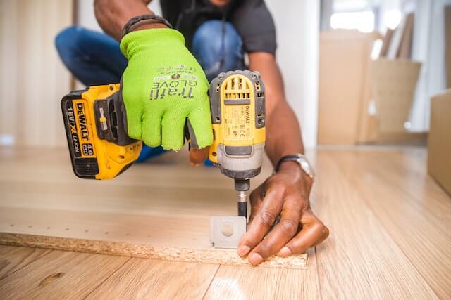 repair-person-using-drill-on-wood