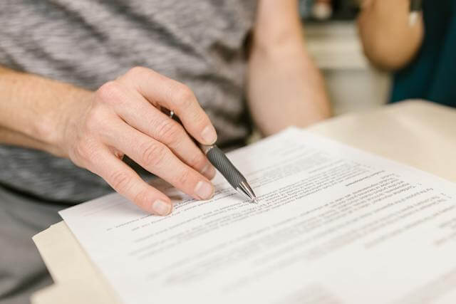 person-holding-a-pen-reading-over-a-lease-agreement