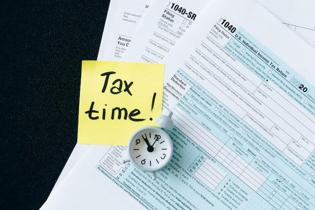tax-documents-on-a-black-table-with-a-sticky-note-that-says-tax-time