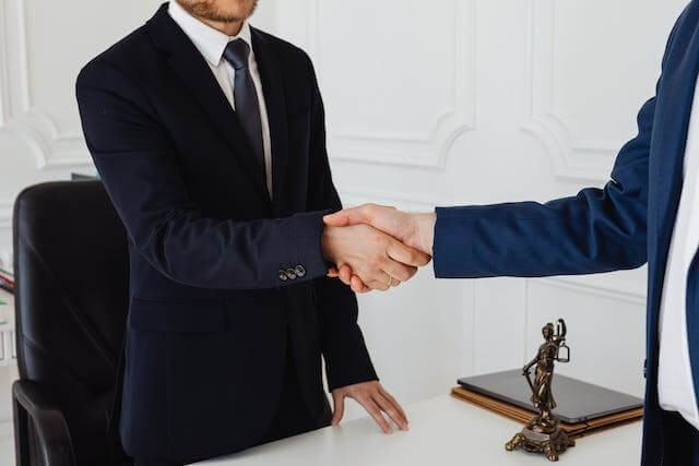 two-business-professionals-shaking-hand-over-desk